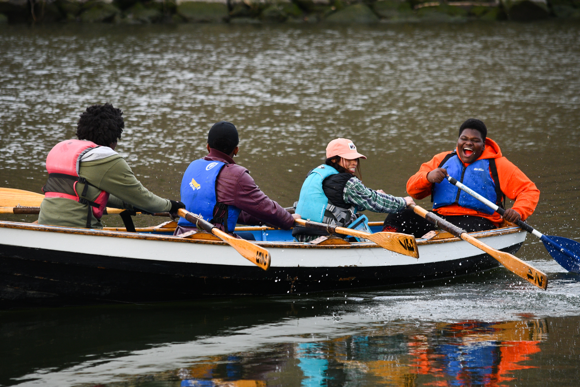 Kids smile from a boat as they paddle on a river